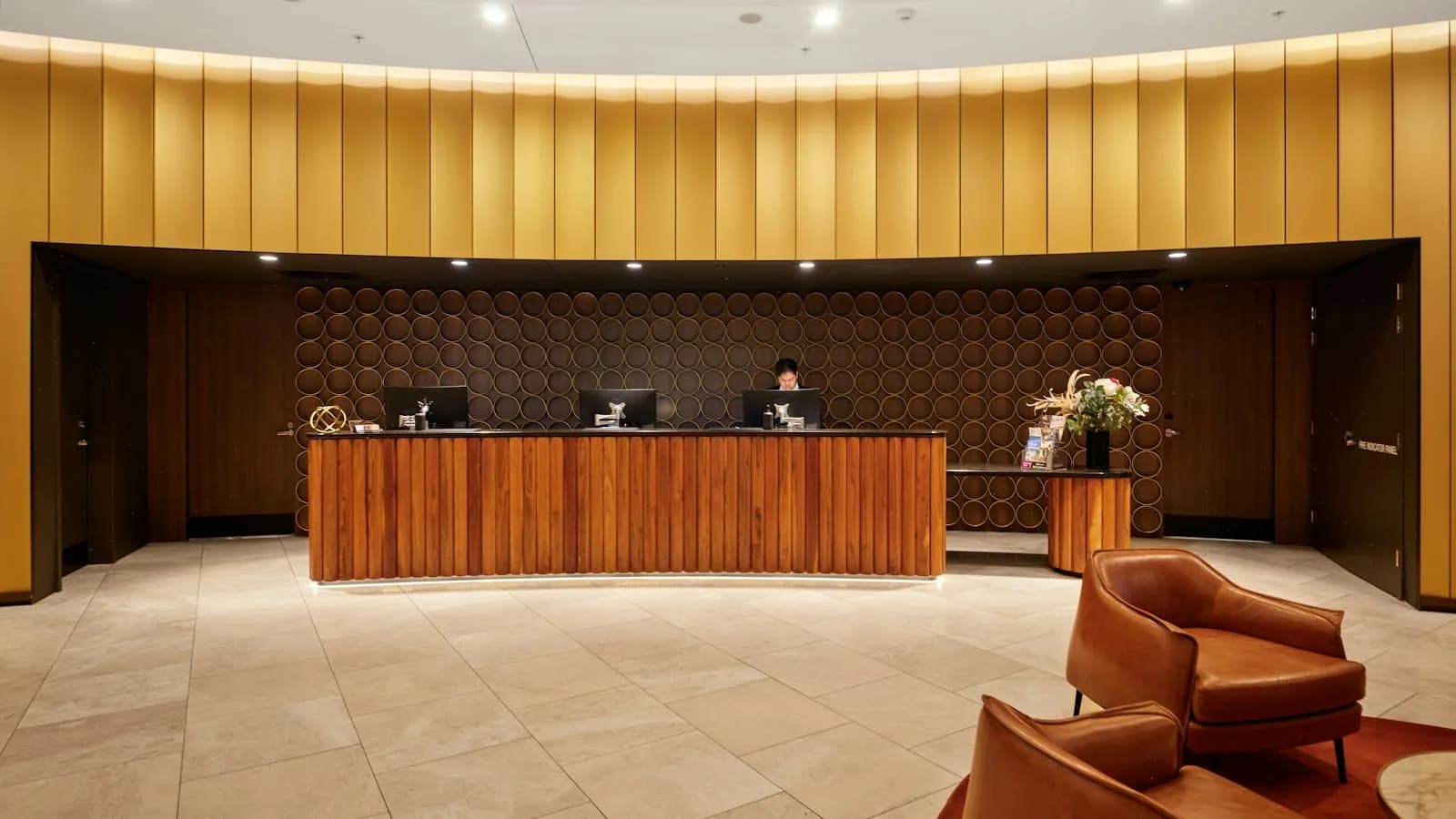 A reception desk in a large wood-panelled lobby with armchairs