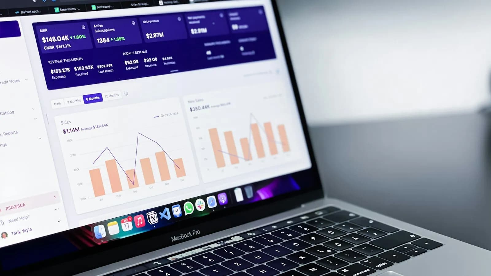 A laptop on a dark desk showing an analytics dashboard with bar and line charts