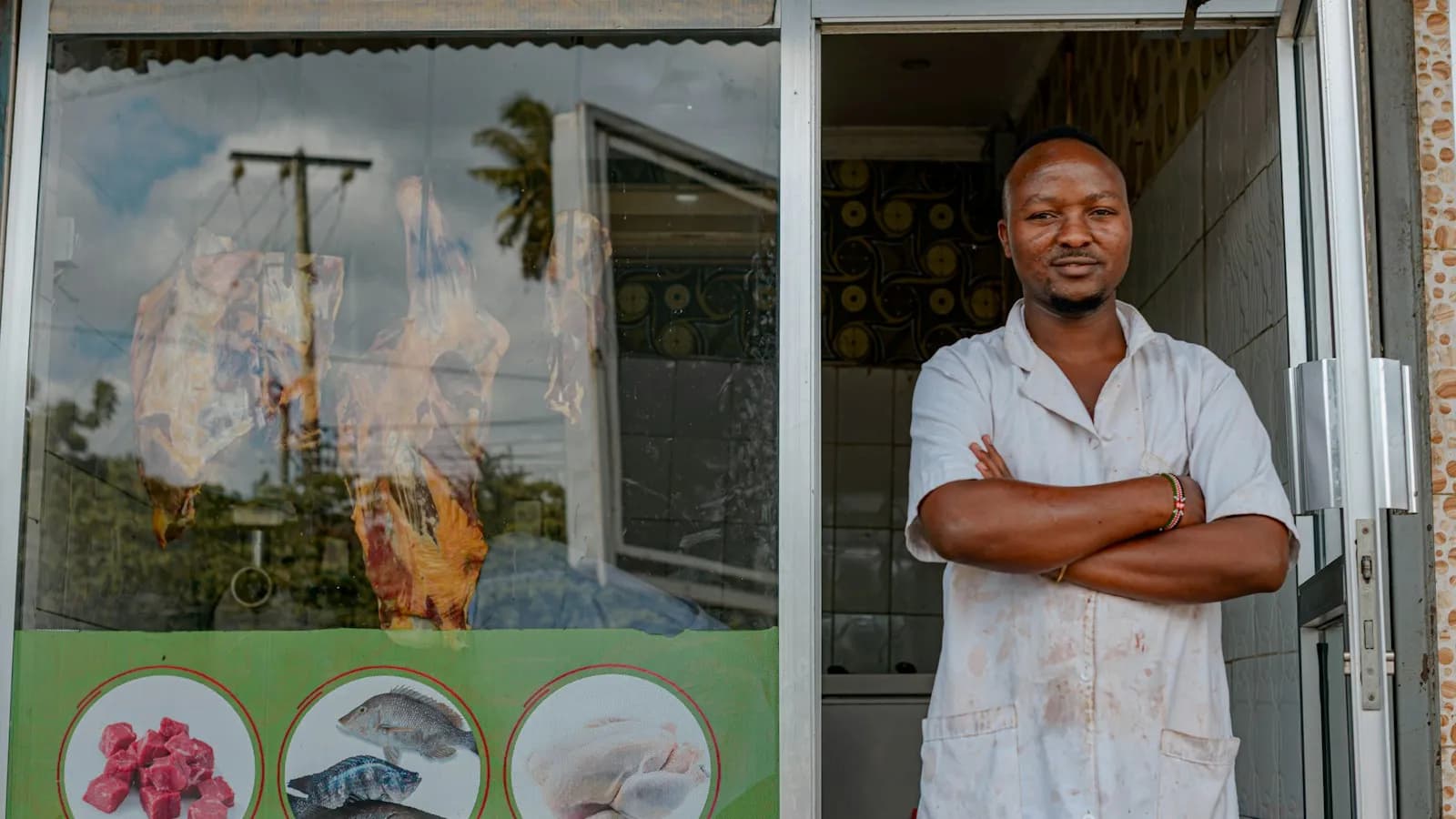 A shop owner standing with folded arms in the doorway of his small store