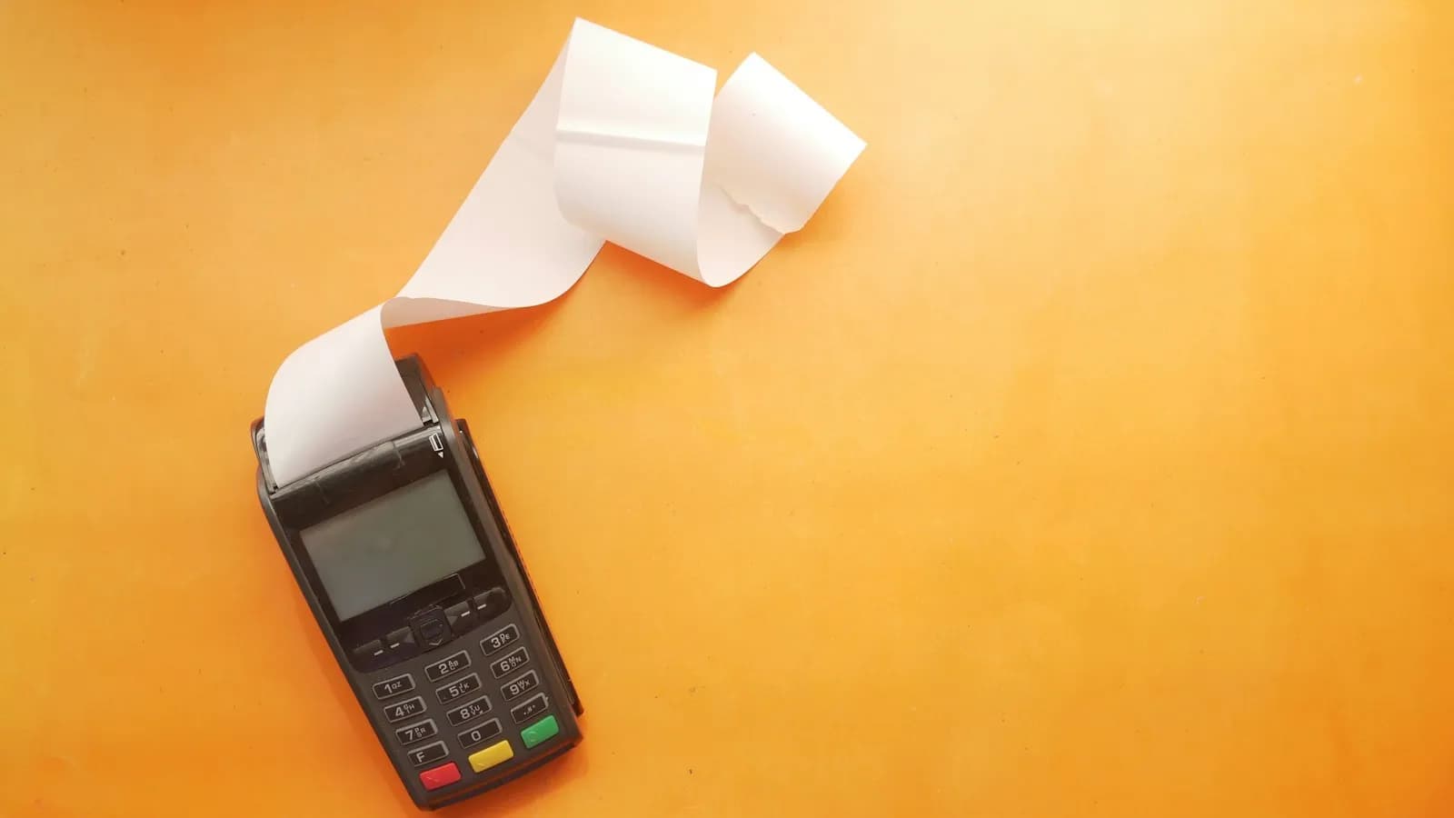 A card payment terminal printing a long receipt on an orange background