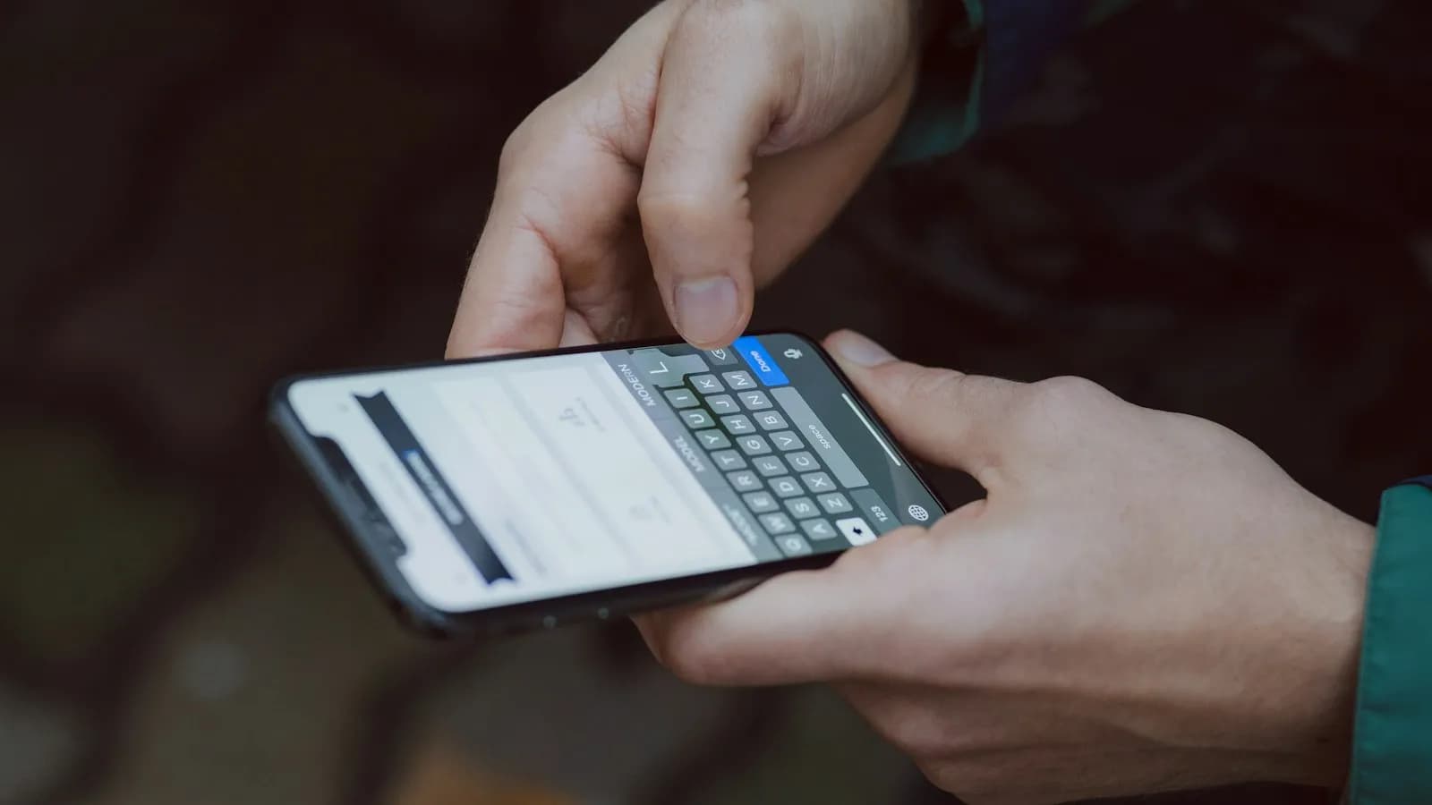 Two hands typing a message on a smartphone