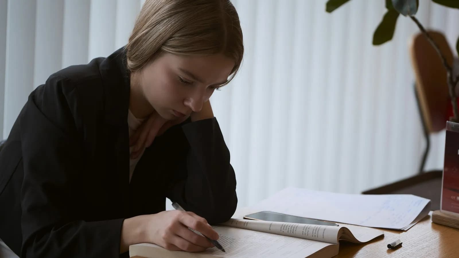A young woman studying at a desk with an open book