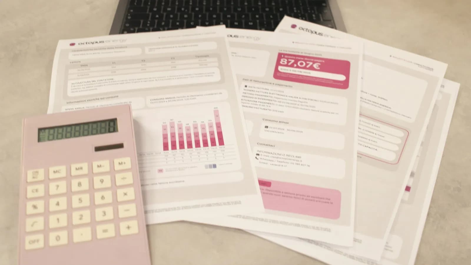 Printed bills with charts next to a pink calculator