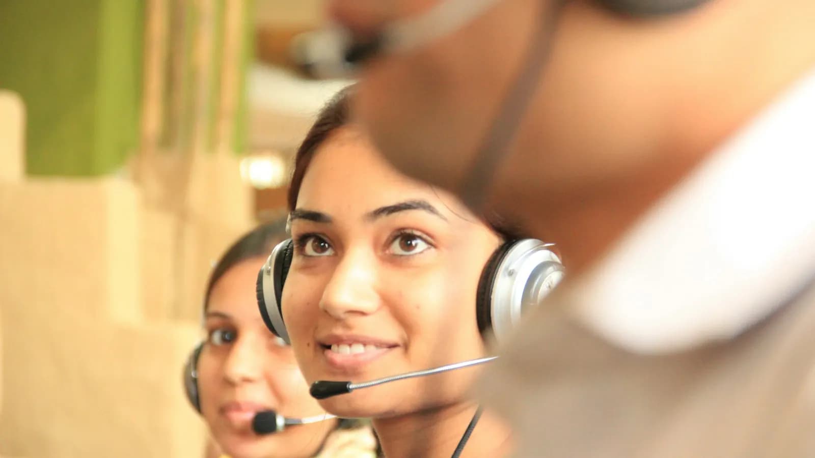 Two women wearing headsets working at a customer support desk