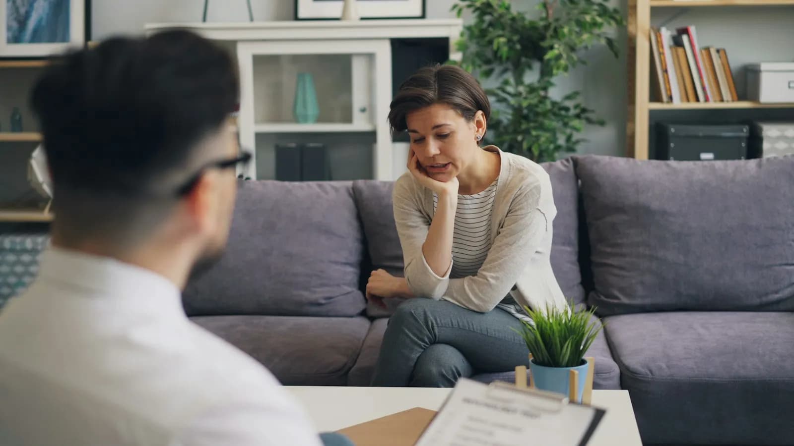 A counsellor sitting across from a student on a sofa, talking in a calm office
