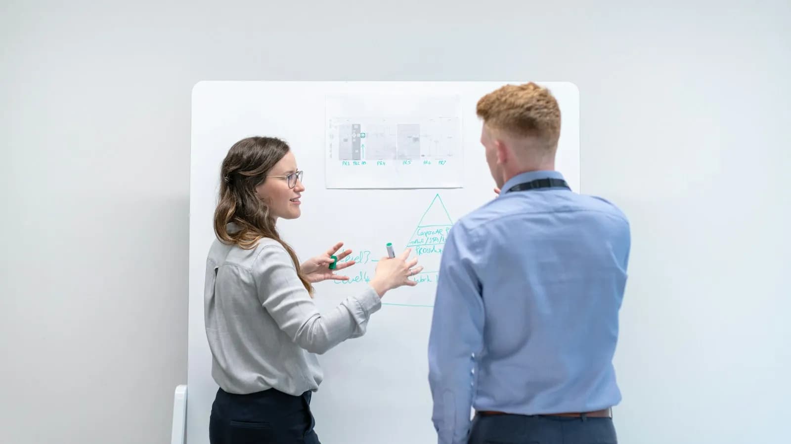 Two colleagues discussing ideas in front of a whiteboard