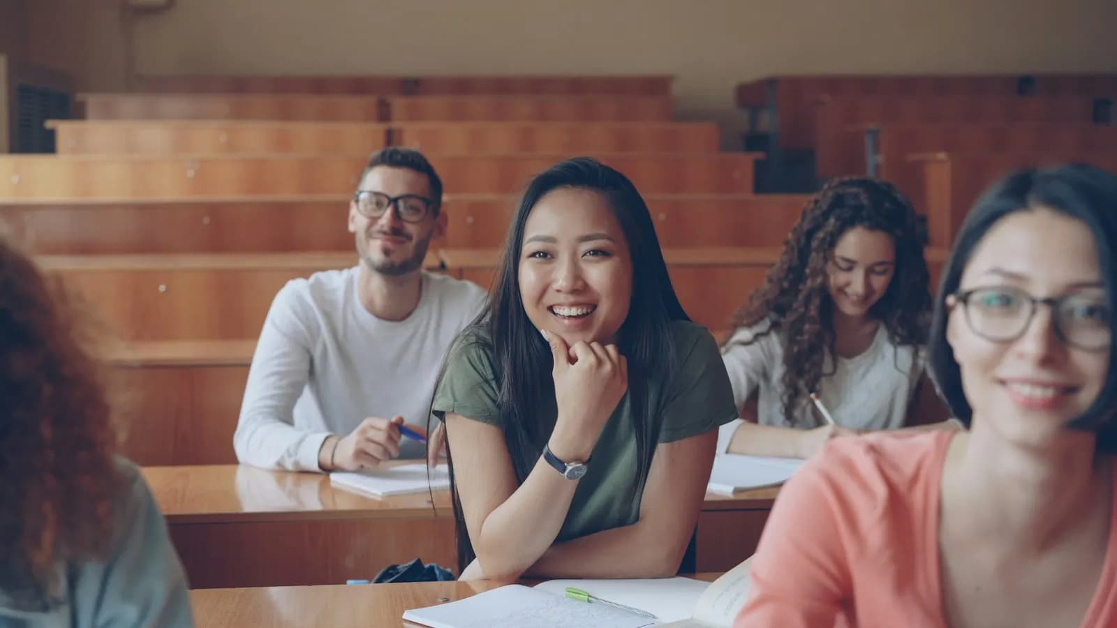 Smiling students sitting in rows in a lecture hall