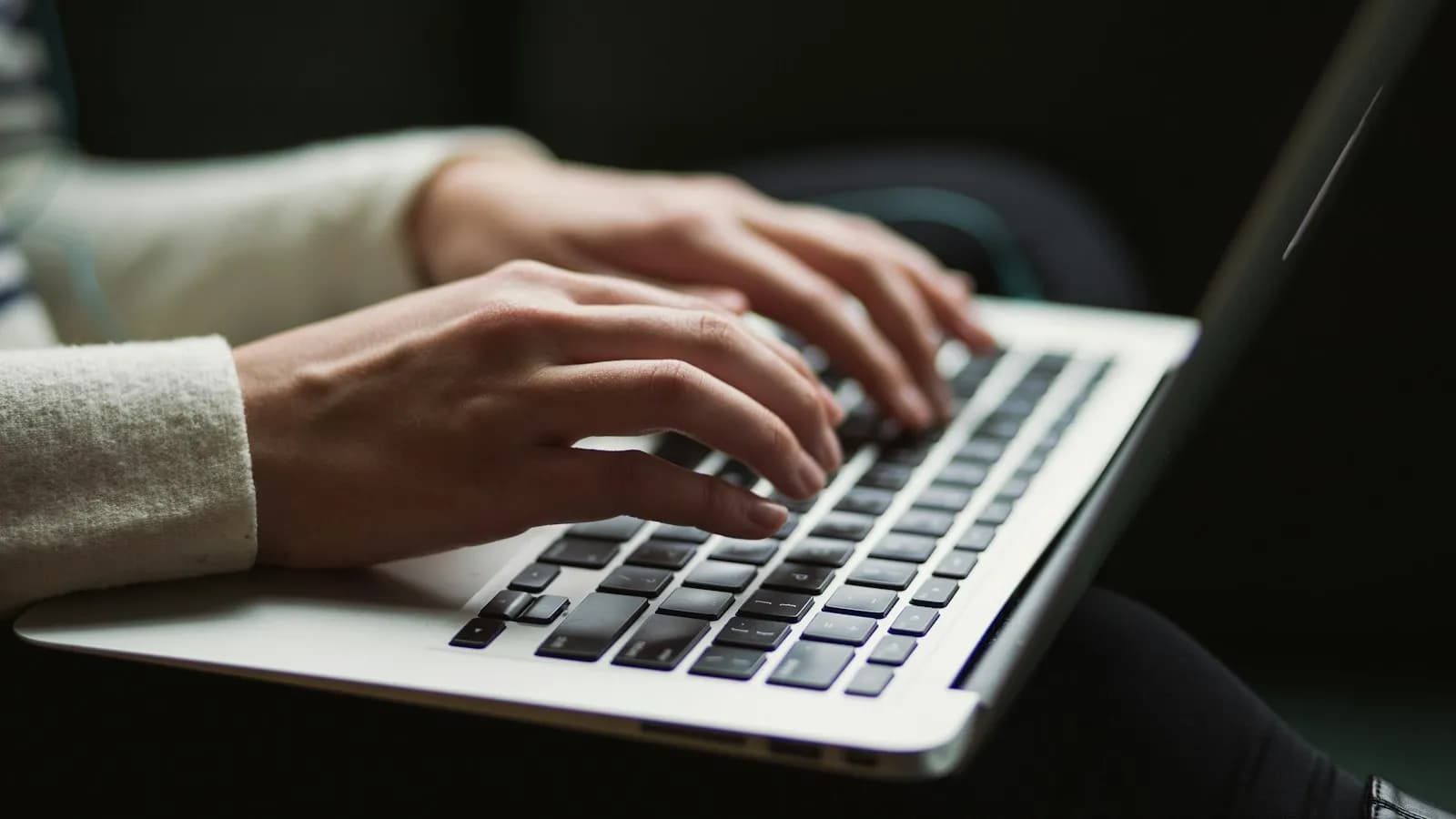 Hands typing on a laptop keyboard