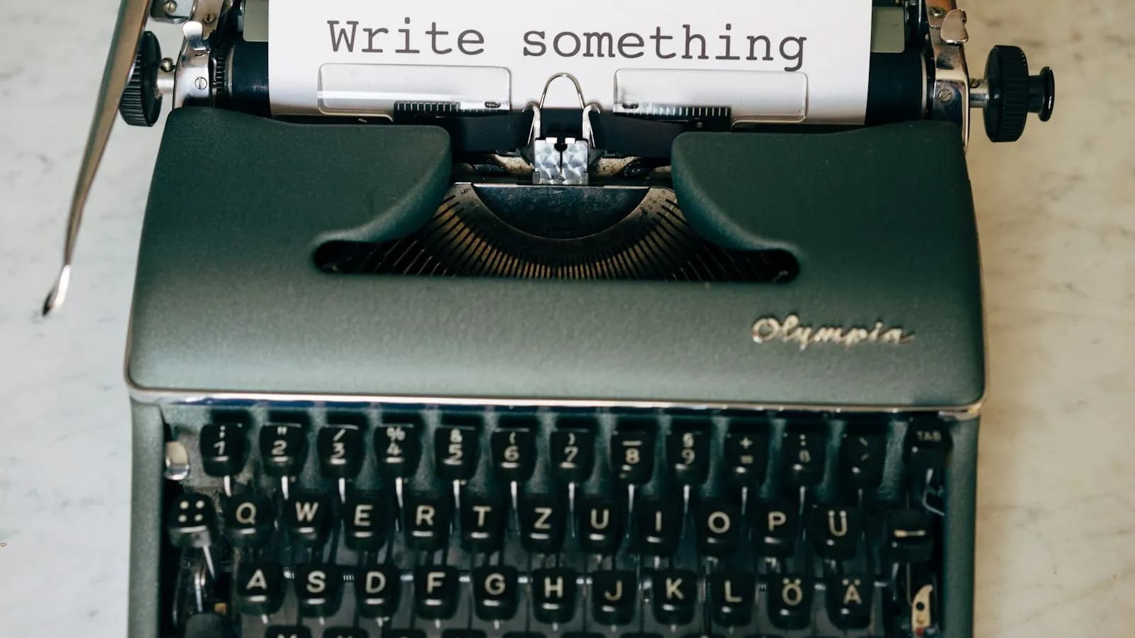 A typewriter with a sheet of paper reading Write something