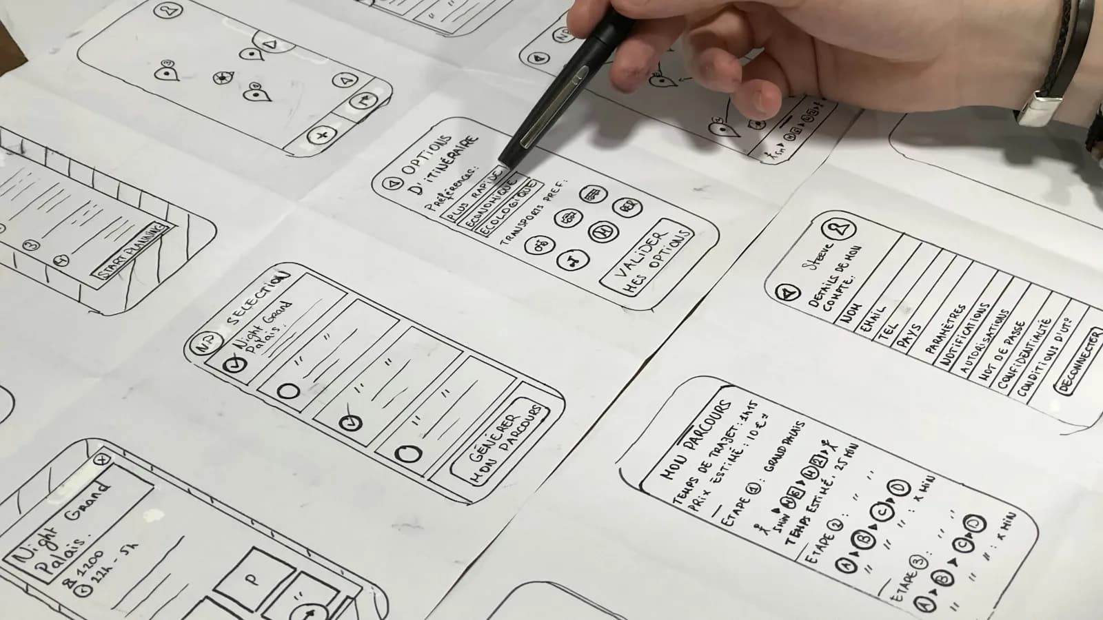 A designer sketching mobile page wireframes on paper with a pen