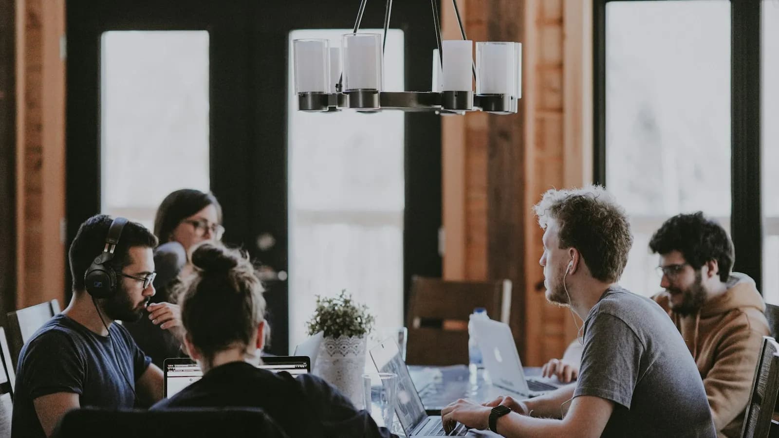 A small team working on laptops around a wooden table in a bright office
