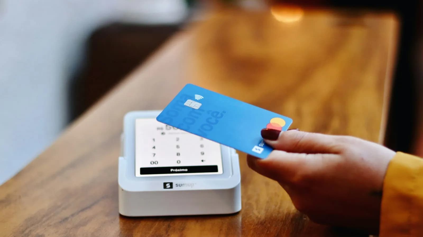 A person holding a payment card in front of a card machine