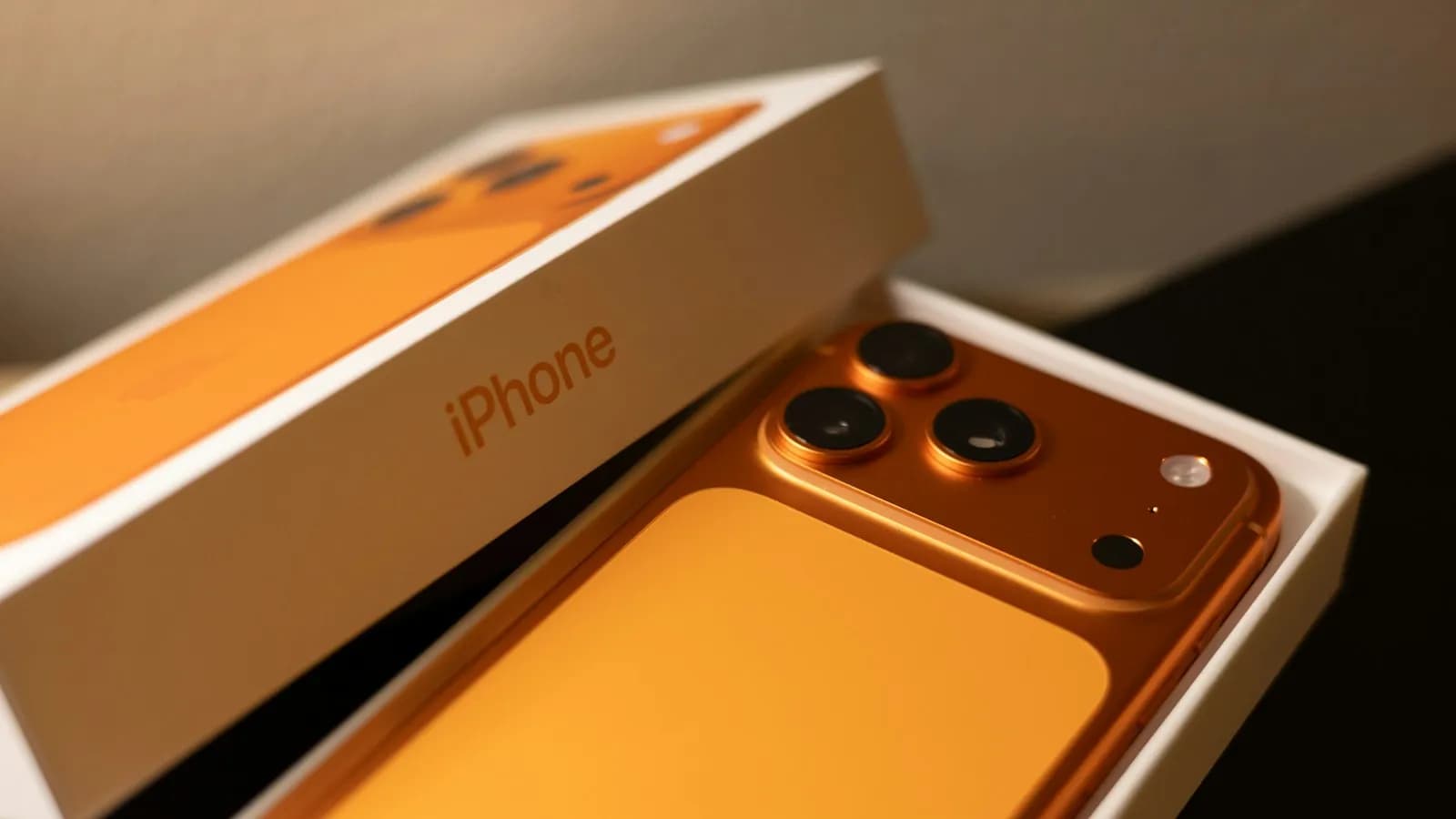An orange smartphone lying in its open white box