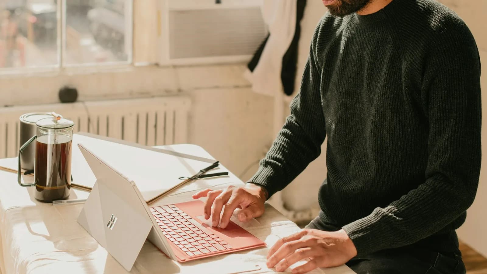 A man working on a laptop at a table in a small office