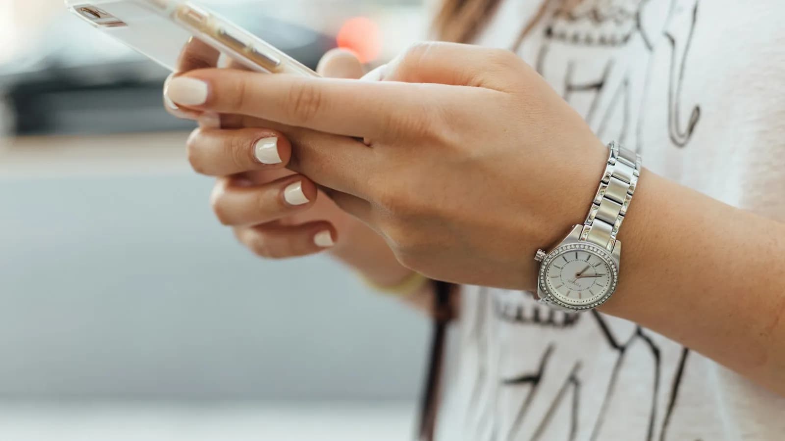 A woman outdoors holding an iPhone and reading a message