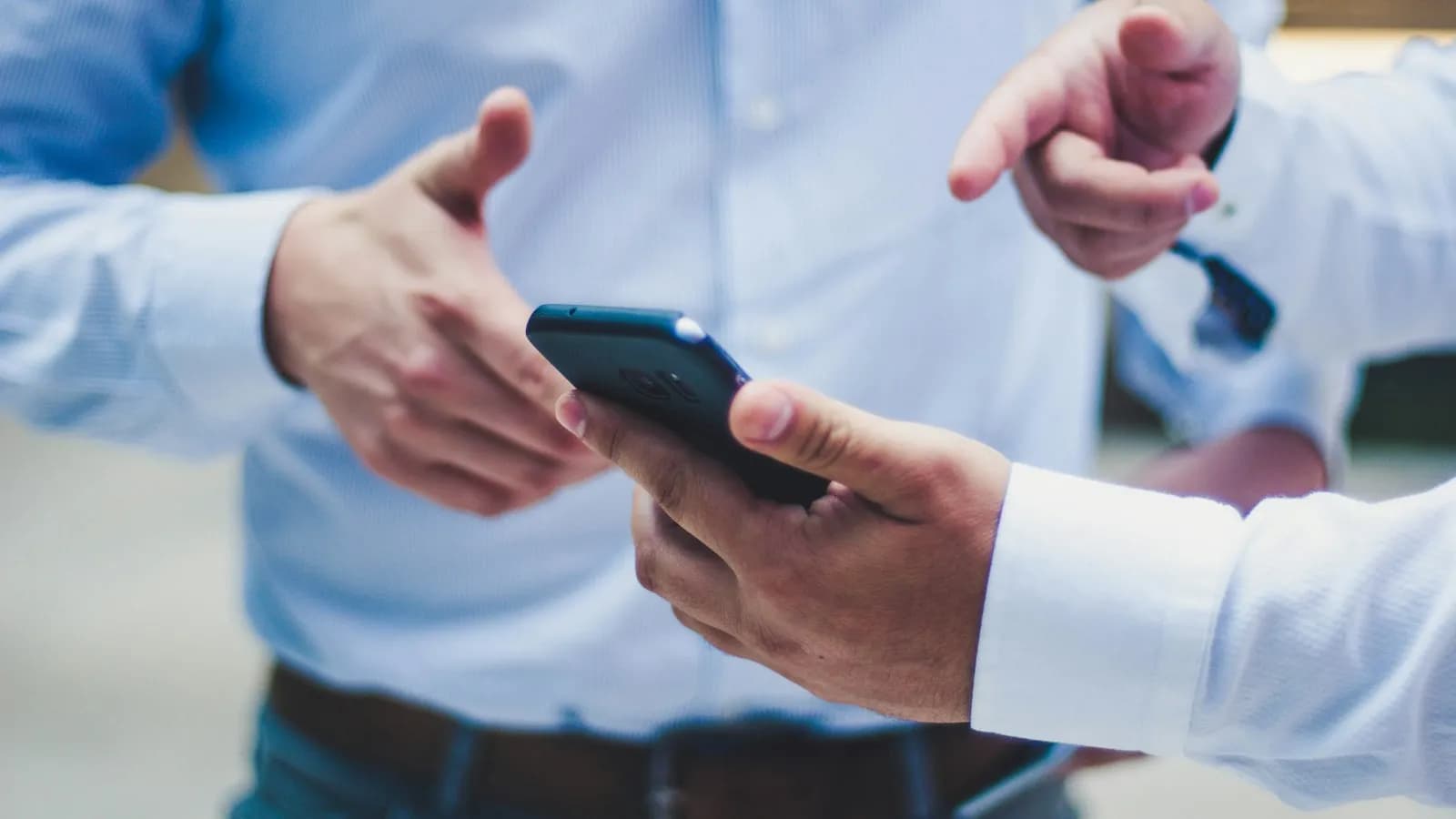 Two people in office shirts looking at a smartphone together