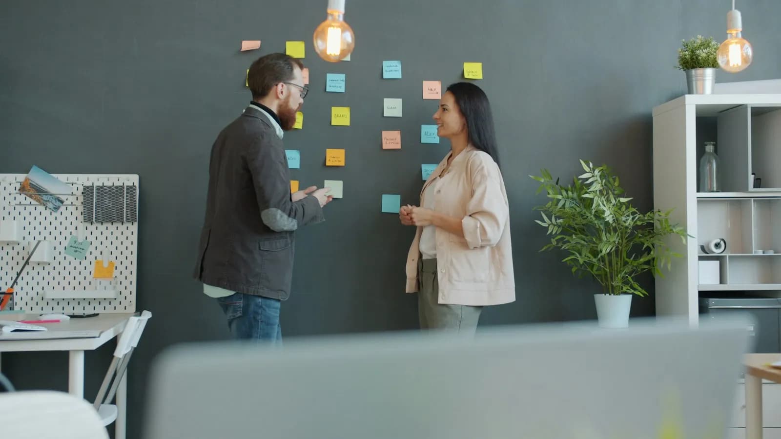 Two colleagues mapping a process with colourful sticky notes on an office wall